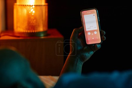 Photo for Closeup of adult man using dating app while laying in bed at night - Royalty Free Image