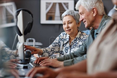 Téléchargez les photos : Portrait d'un homme et d'une femme âgés regardant un écran d'ordinateur en classe de technologie pour personnes âgées - en image libre de droit