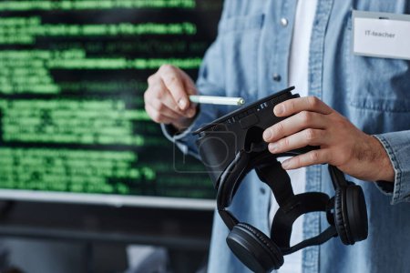 Photo for Closeup of man holding VR headset against screen with code lines while developing virtual reality software, copy space - Royalty Free Image