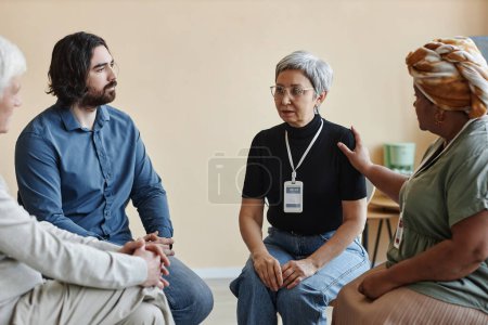 Photo for Group of senior people sitting in circle at mental health support group with mature Asian woman sharing - Royalty Free Image