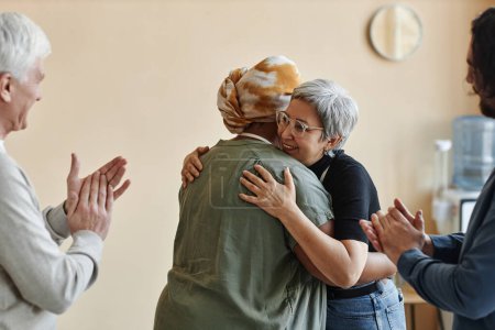 Foto de Diverso grupo de personas mayores aplaudiendo y abrazando celebrando en grupo de apoyo - Imagen libre de derechos