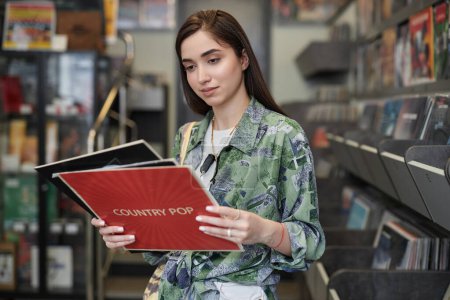 Photo for Waist up portrait of young woman choosing vinyl records in record store, copy space - Royalty Free Image