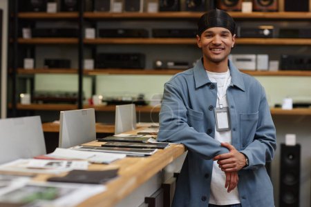 Foto de Retrato de la cintura hacia arriba del joven negro que trabaja en la tienda de tecnología y sonríe a la cámara, espacio para copiar - Imagen libre de derechos