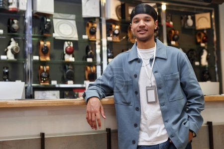 Photo for Waist up portrait of smiling young man working in music store and standing by counter looking at camera, copy space - Royalty Free Image