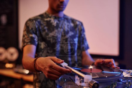 Téléchargez les photos : Gros plan de jeune homme noir jouant des disques vinyle au tourne-disque à la maison, espace de copie - en image libre de droit