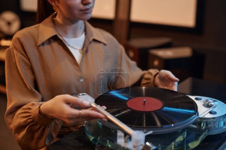 Téléchargez les photos : Gros plan de jeune femme jouant des disques vinyle à la maison dans un cadre confortable, espace de copie - en image libre de droit