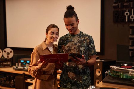 Photo for Waist up portrait of young couple holding vnyl records while enjoying music at home studio, copy space - Royalty Free Image