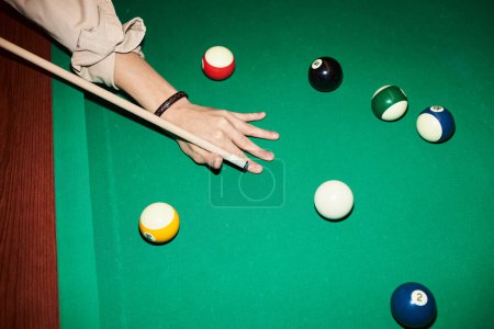 Photo for Top view closeup of male hand holding cue stick and playing billiard at green pool table with camera flash copy space - Royalty Free Image