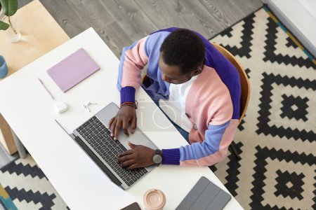 Foto de Vista superior en el hombre negro que trabaja con el ordenador portátil en el interior de la oficina creativa, espacio de copia - Imagen libre de derechos