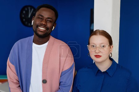 Téléchargez les photos : Portrait vibrant de deux hommes d'affaires créatifs portant des vêtements colorés au bureau et souriant à la caméra - en image libre de droit