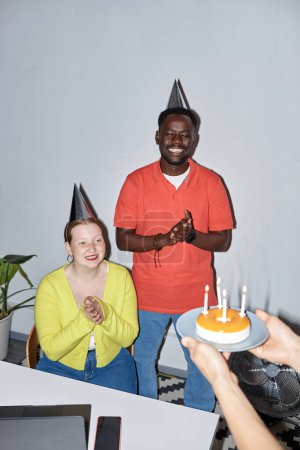 Photo for Vertical portrait of young people celebrating birthday in office, shot with flash - Royalty Free Image