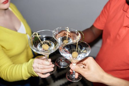 Foto de Primer grupo de jóvenes sosteniendo vasos y brindando bebiendo martini en la fiesta, filmados con flash - Imagen libre de derechos