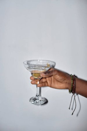 Foto de Mínimo primer plano del joven sosteniendo un vaso de martini durante la fiesta, disparado con flash - Imagen libre de derechos