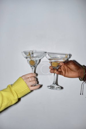 Photo for Minimal closeup of two young people holding glasses and toasting drinking martini during party, shot with flash - Royalty Free Image