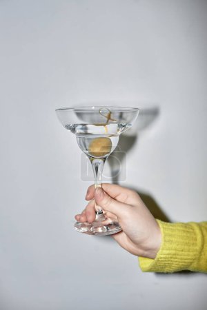 Photo for Minimal closeup of young woman holding martini glass during party, shot with flash - Royalty Free Image