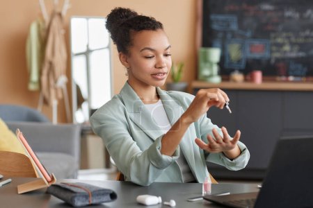 Foto de Retrato de una elegante mujer de negocios negra haciendo manicura en el lugar de trabajo en la oficina y usando esmalte de uñas, espacio para copiar - Imagen libre de derechos