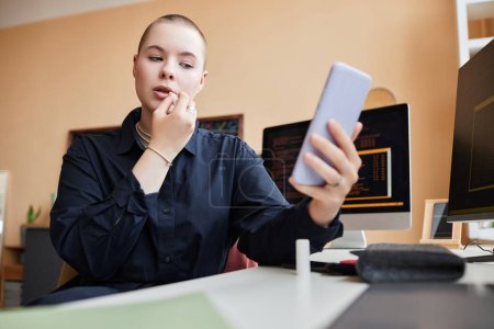 Foto de Retrato de bajo ángulo de la joven mujer de negocios calva haciendo maquillaje en el lugar de trabajo en la oficina y el uso de lápiz labial, espacio de copia - Imagen libre de derechos