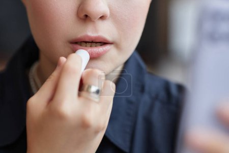 Foto de Primer plano mínimo de la mujer joven que hace el maquillaje y el uso de color de lápiz labial desnudo mirando en el espejo, espacio de copia - Imagen libre de derechos