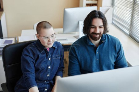 Téléchargez les photos : Deux jeunes ingénieurs informatiques professionnels assis devant un écran d'ordinateur et regardant une vidéo en ligne décrivant les points de base de la cybersécurité - en image libre de droit