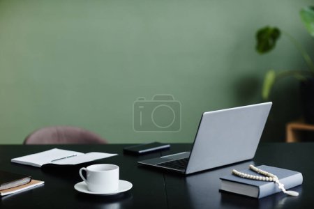 Téléchargez les photos : Image de fond minimale du bureau avec ordinateur portable ouvert contre le mur vert, espace de copie - en image libre de droit