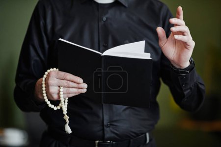 Photo for Close up of senior priest holding Bible and rosary while reading prayer - Royalty Free Image
