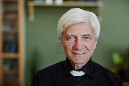 Photo for Close up portrait of white haired senior priest smiling at camera in office setting, copy space - Royalty Free Image