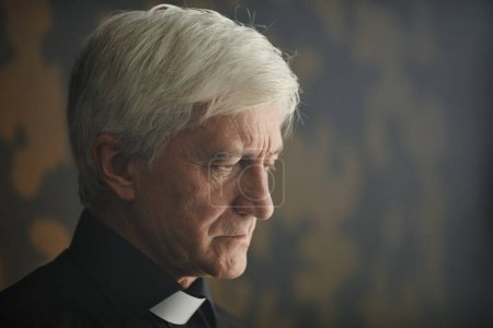 Photo for Close up side view portrait of white haired senior man in clerical collar with serene lighting, copy space - Royalty Free Image