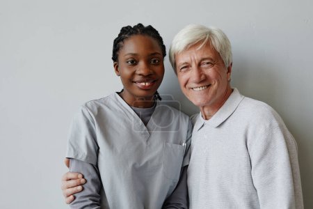 Téléchargez les photos : Portrait taille haute de jeune femme noire comme infirmière et homme âgé souriant à la caméra ensemble - en image libre de droit