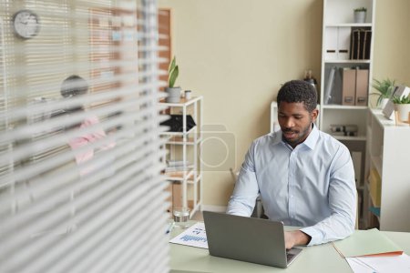 Téléchargez les photos : Portrait d'un homme afro-américain adulte travaillant avec un ordinateur portable au bureau, espace de copie - en image libre de droit