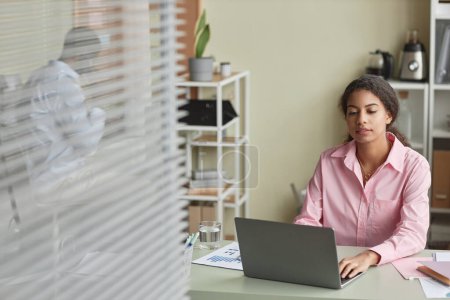 Téléchargez les photos : Portrait d'une femme afro-américaine adulte travaillant avec un ordinateur au bureau, espace de copie - en image libre de droit