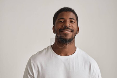 Téléchargez les photos : Portrait minimal d'un bel homme noir posant en studio sur fond blanc - en image libre de droit