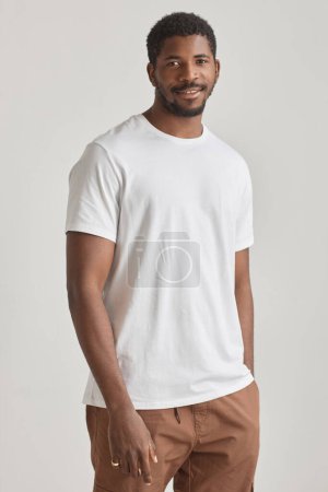 Téléchargez les photos : Portrait minimal d'un bel homme noir posant en studio sur fond blanc portant une chemise blanche - en image libre de droit