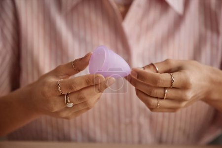 Téléchargez les photos : Minimal close up of unidentifiable woman holding pink menstrual cup against pink shirt copy space - en image libre de droit