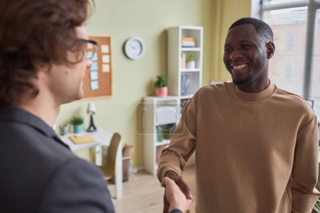 Téléchargez les photos : Portrait d'un homme noir souriant serrant la main d'un collègue au bureau profitant du premier jour d'un nouvel emploi - en image libre de droit