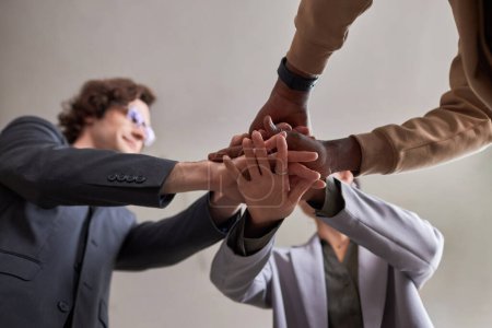 Foto de Vista de bajo ángulo en diverso equipo de negocios uniendo sus manos en unidad celebrando el éxito - Imagen libre de derechos