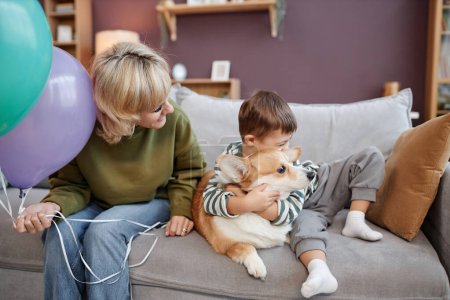Téléchargez les photos : Portrait de mère et de fils atteints du syndrome du duvet câlins avec chien assis sur le canapé ensemble - en image libre de droit