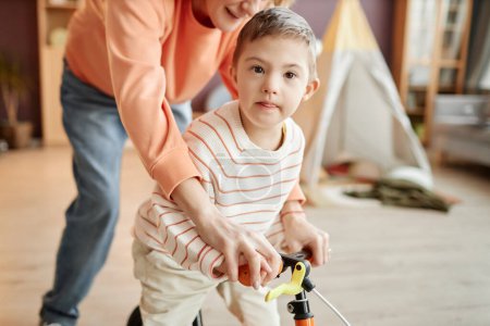 Photo for Portrait of little boy with down syndrome playing with runbike and looking at camera - Royalty Free Image