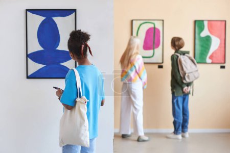 Téléchargez les photos : Vue arrière de divers groupes d'adolescents regardant l'art abstrait dans une galerie d'art moderne ou un musée, espace de copie - en image libre de droit