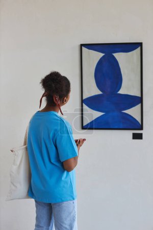 Photo for Vertical back view of teenager looking at abstract art in art gallery or museum, copy space - Royalty Free Image