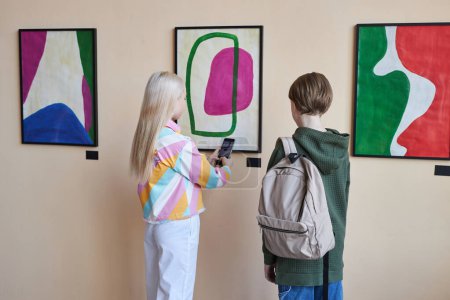Téléchargez les photos : Vue arrière minimale chez deux adolescents Groupe diversifié d'adolescents regardant l'art abstrait dans la galerie d'art ou le musée debout en rangée, espace de copie - en image libre de droit