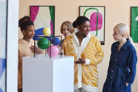 Foto de Diverso grupo de teenas escuchando al maestro o guía turístico en la galería de arte moderno - Imagen libre de derechos