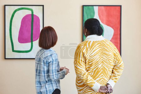 Photo for Colorful back view of two people looking at abstract art painting in modern art gallery or museum - Royalty Free Image