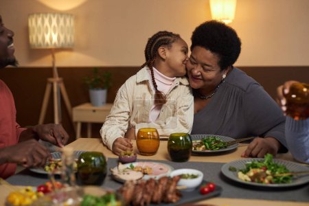Foto de Retrato de niña afroamericana besando a la abuela en la mejilla en la mesa de la cena con espacio de copia familiar - Imagen libre de derechos