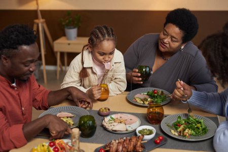 Téléchargez les photos : Vue grand angle à la grande famille afro-américaine dîner ensemble assis à la table à la maison - en image libre de droit