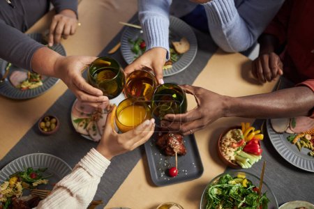 Téléchargez les photos : Vue de dessus gros plan de grands afro-américains famille cliquetis verres dans la célébration sur la table du dîner - en image libre de droit