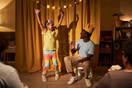 Foto de Retrato de larga duración de linda chica negra dando concierto en casa para padres y familia con padre participando en la actuación - Imagen libre de derechos