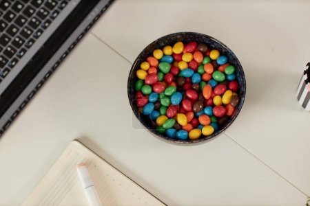 Foto de Imagen de fondo de vista superior mínima de mesa blanca o escritorio en la oficina con enfoque en un tazón de dulces de colores - Imagen libre de derechos