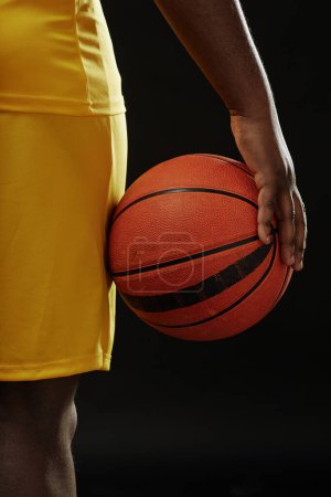 Photo for Close up of African American basketball player holding ball against black background - Royalty Free Image