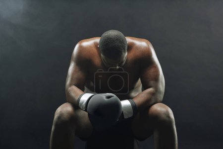 Foto de Retrato dramático retroiluminado de un gran boxeador musculoso sentado y descansando con humo en el fondo - Imagen libre de derechos