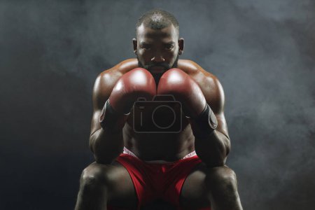 Photo for Dramatic front view portrait of muscular African American boxer looking at camera intensely with smoke in background - Royalty Free Image